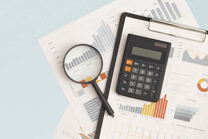 Business graphs, charts, magnifying glass and calculator on tabl Bookkeeping Services